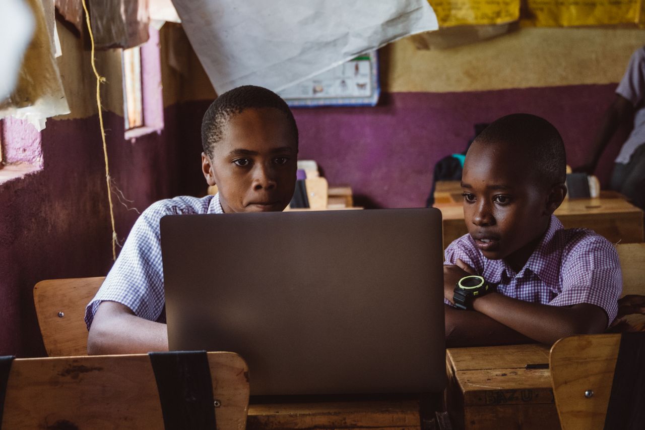Two boys attentively studying with a laptop in a classroom, enhancing their learning experience.